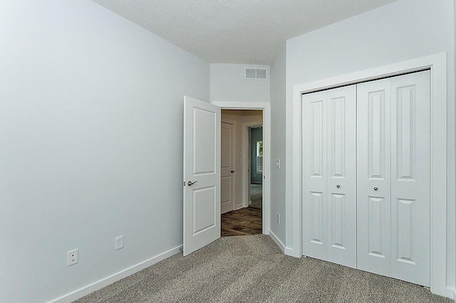 unfurnished bedroom with a textured ceiling, a closet, and carpet flooring