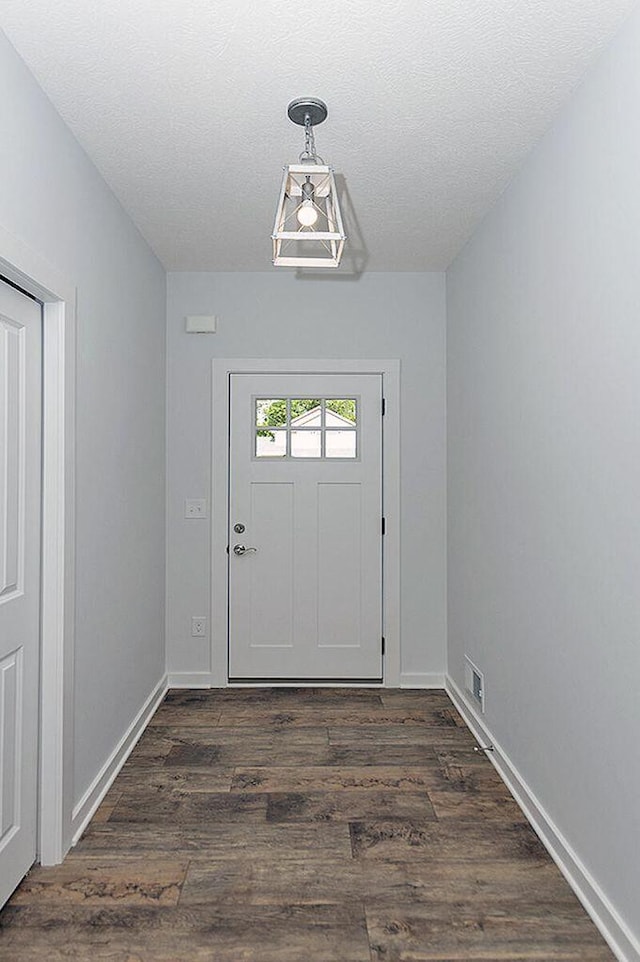doorway to outside with dark hardwood / wood-style flooring and a textured ceiling