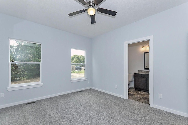 unfurnished bedroom with ceiling fan, ensuite bath, carpet floors, and a textured ceiling