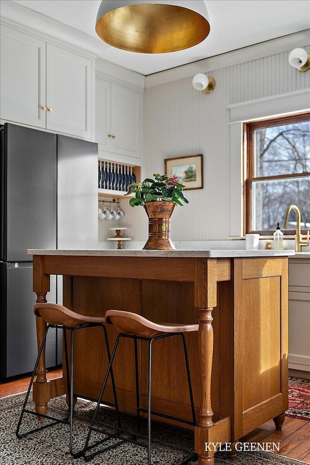 bar with a sink, wood finished floors, and freestanding refrigerator