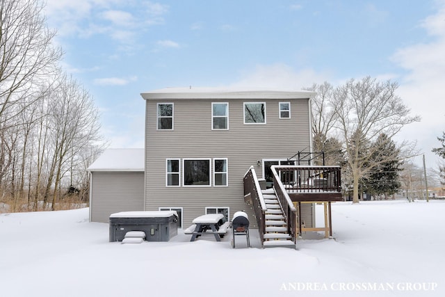 snow covered house with a hot tub, stairway, and a deck