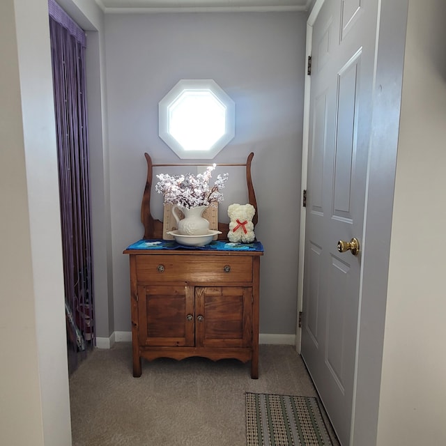 hall with baseboards and light colored carpet