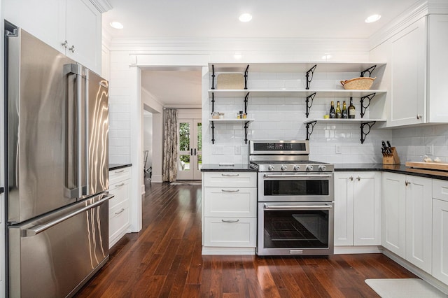 kitchen featuring dark wood-type flooring, stainless steel appliances, white cabinets, crown molding, and backsplash