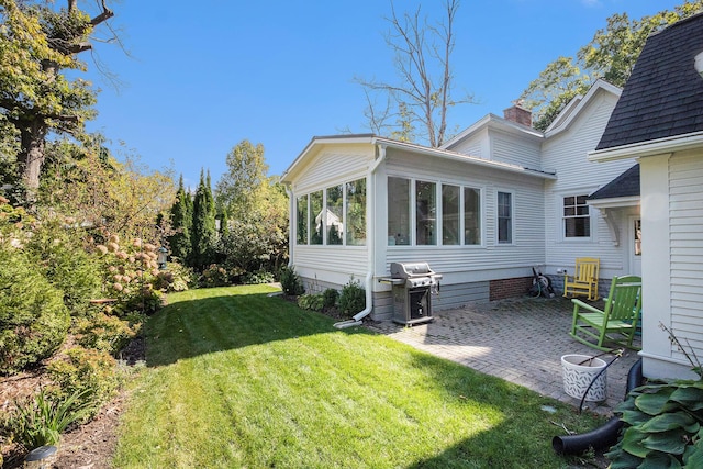 rear view of property with a patio, a sunroom, and a lawn