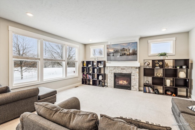 living room with baseboards, carpet flooring, a stone fireplace, and a textured ceiling