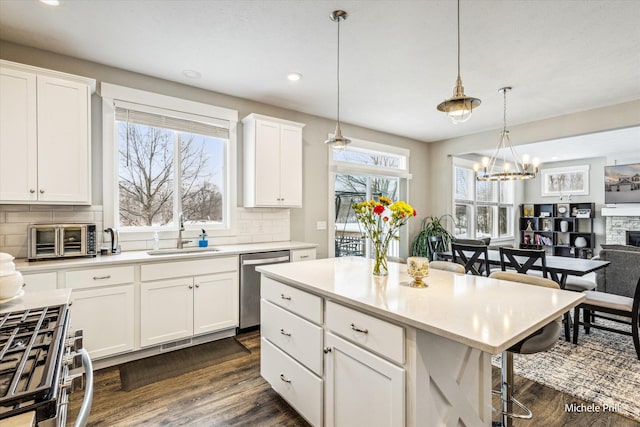 kitchen featuring light countertops, appliances with stainless steel finishes, a sink, and decorative light fixtures