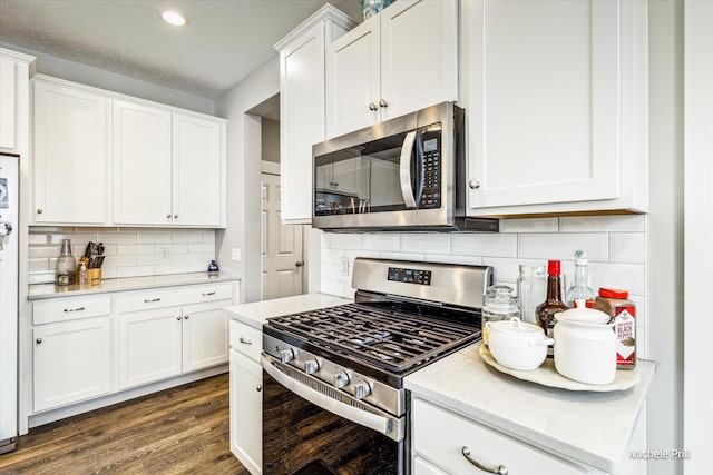 kitchen featuring decorative backsplash, dark wood-style flooring, light stone countertops, stainless steel appliances, and white cabinetry