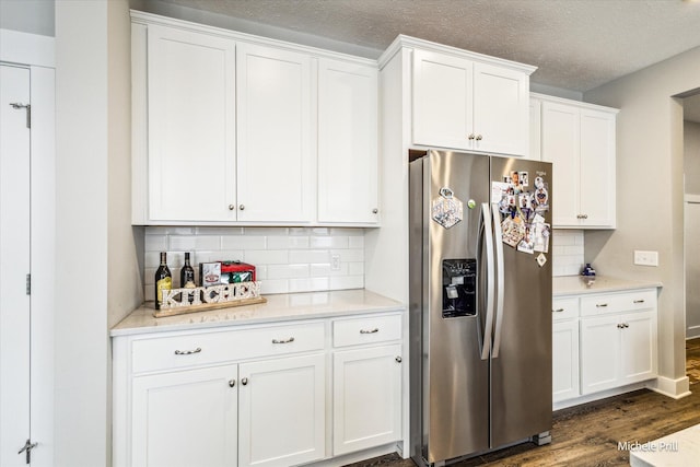 kitchen featuring a textured ceiling, dark wood finished floors, white cabinets, backsplash, and stainless steel fridge