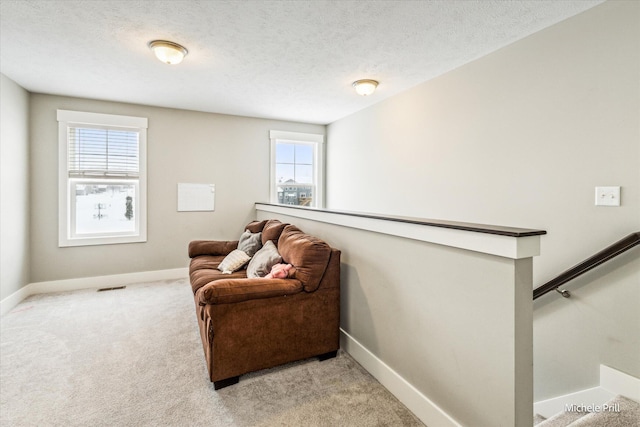 sitting room with baseboards, light colored carpet, visible vents, and an upstairs landing