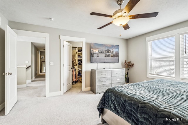 bedroom with a textured ceiling, light carpet, baseboards, a spacious closet, and a closet