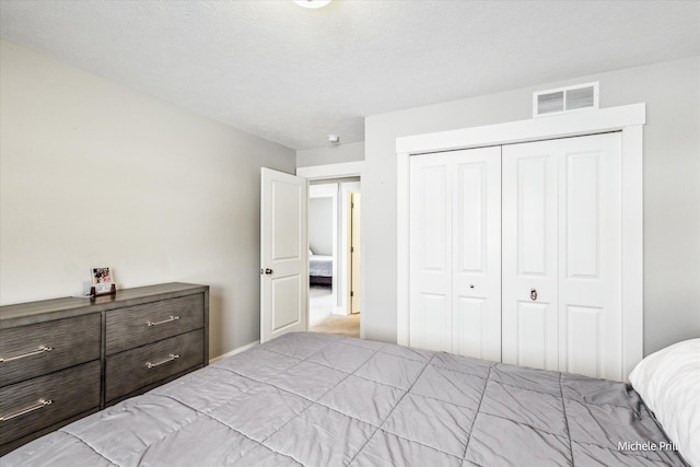 bedroom with a textured ceiling, a closet, and visible vents