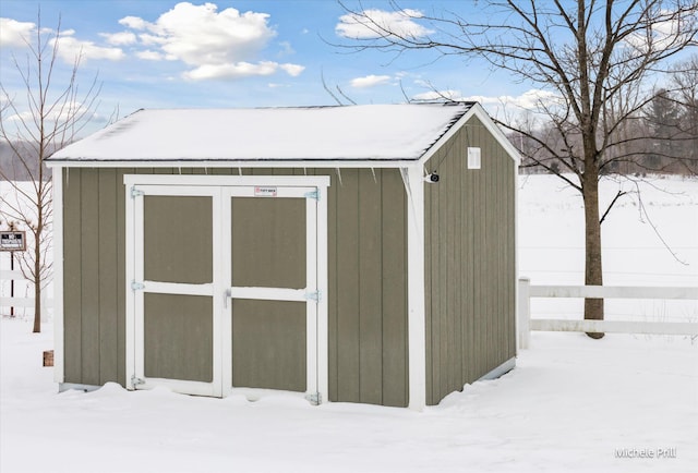 snow covered structure featuring an outbuilding and a shed