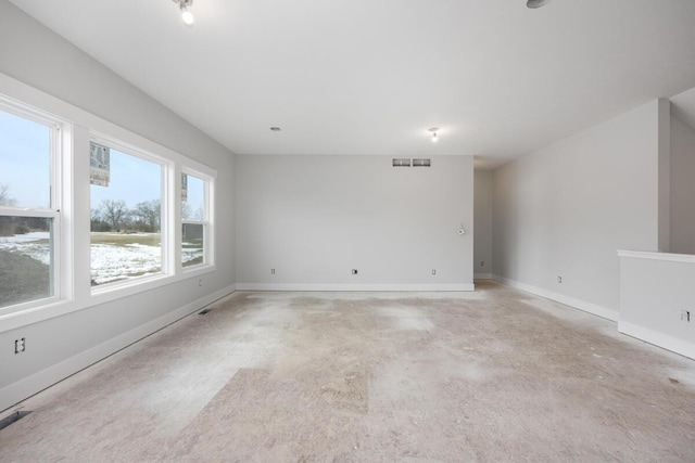 spare room featuring baseboards, visible vents, and concrete flooring