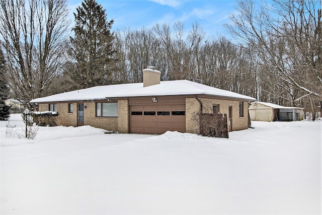 exterior space featuring an attached garage, a chimney, and brick siding