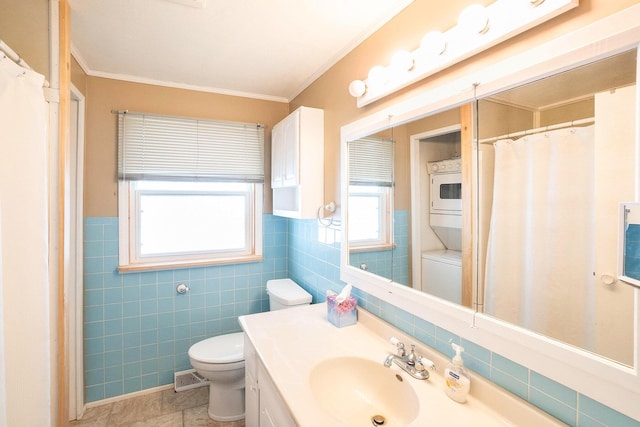 5274 N Bahr Dr Unit 14, Irons, MI 49644 - full bath with stacked washing machine and dryer, toilet, vanity, crown molding, and tile walls