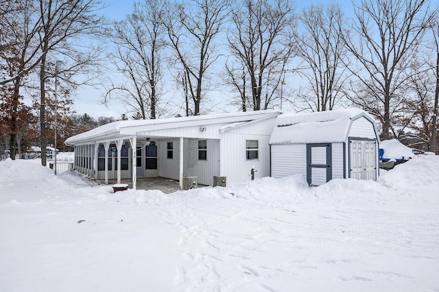 snow covered rear of property featuring a sunroom