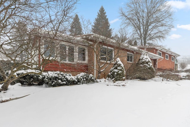 view of snowy exterior featuring brick siding