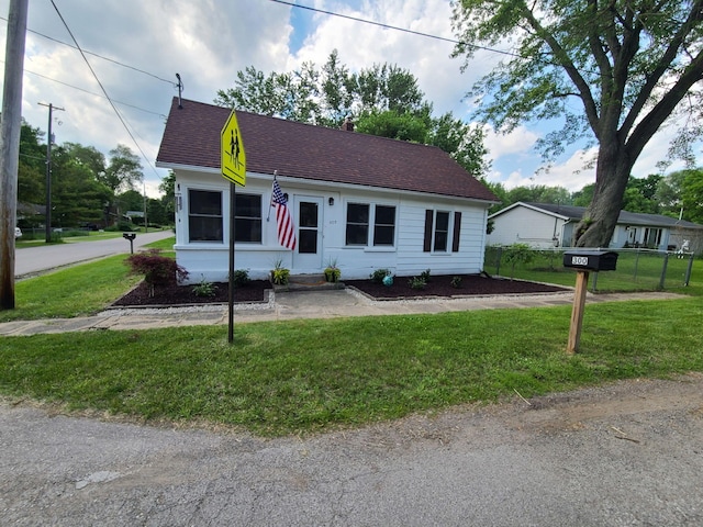 view of front of home featuring roof with shingles and a front yard