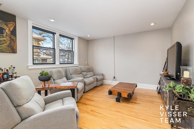 living area with baseboards, light wood finished floors, and recessed lighting