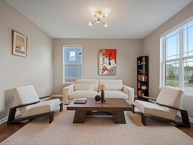 living room featuring an inviting chandelier, baseboards, and wood finished floors