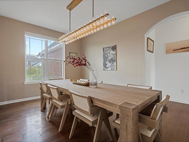 dining space with arched walkways, dark wood-style flooring, and baseboards