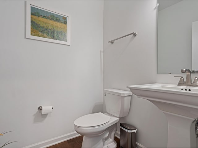 half bathroom with toilet, baseboards, and wood finished floors