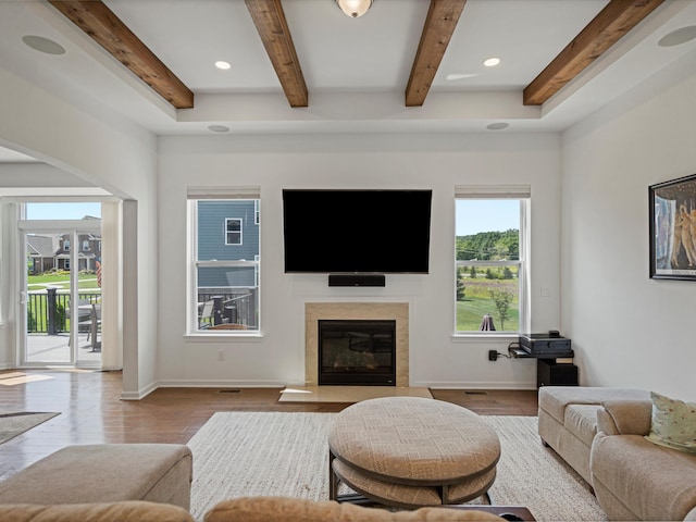 living room with light wood-type flooring, a fireplace, beamed ceiling, and baseboards