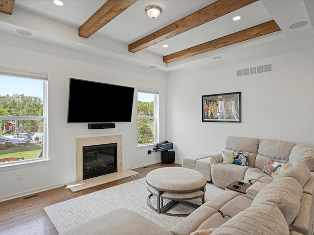 living room with a premium fireplace, light wood-type flooring, visible vents, and baseboards