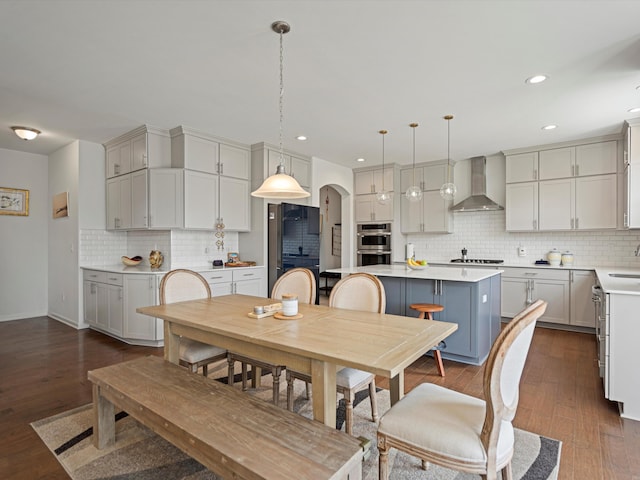 dining space with arched walkways, dark wood-style flooring, and recessed lighting