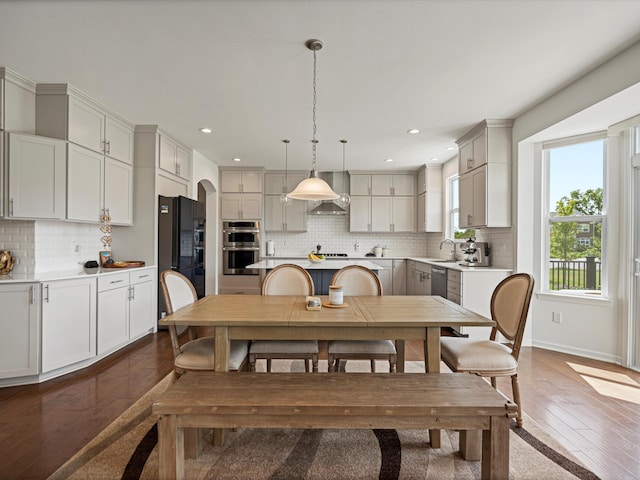 dining room with arched walkways, recessed lighting, baseboards, and wood finished floors