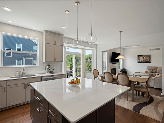 kitchen featuring gray cabinetry, dark wood-type flooring, open floor plan, a sink, and dishwasher