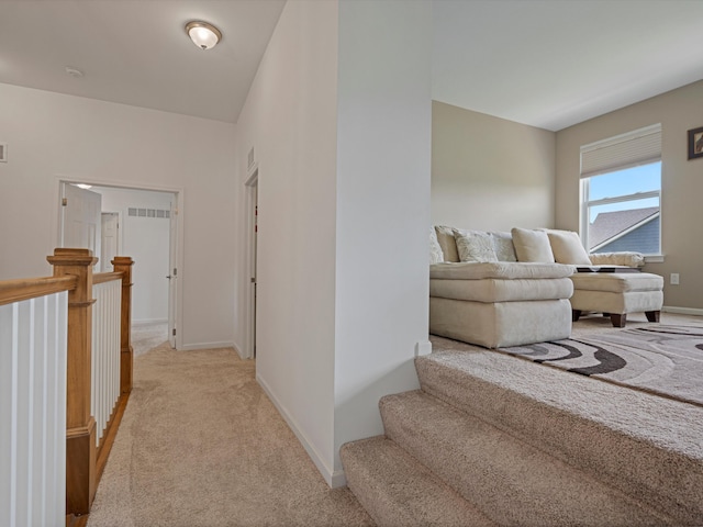 hallway with light carpet, visible vents, and baseboards