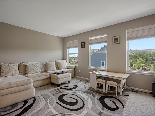 living room featuring a healthy amount of sunlight, baseboards, and light colored carpet