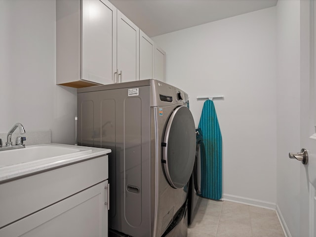 clothes washing area with light tile patterned flooring, a sink, baseboards, cabinet space, and washer / clothes dryer