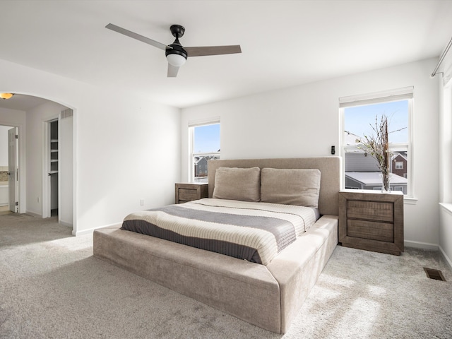 bedroom with arched walkways, baseboards, visible vents, and light colored carpet