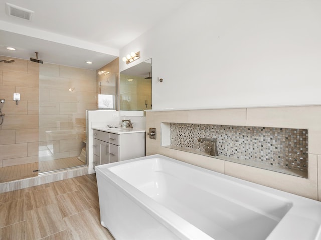 full bathroom with a shower stall, visible vents, a bath, and vanity