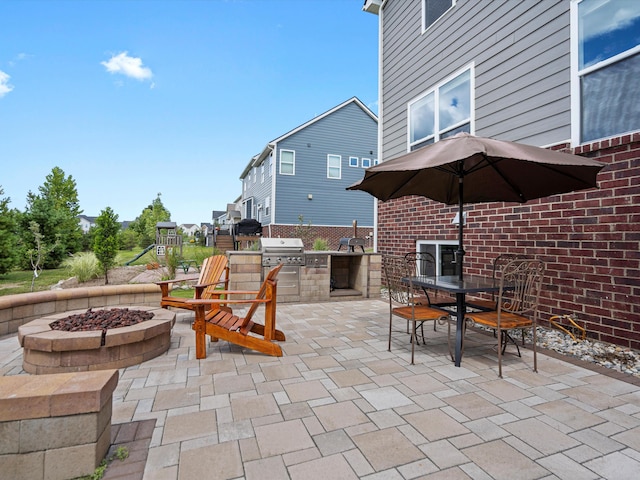 view of patio featuring outdoor dining area, grilling area, a fire pit, and an outdoor kitchen