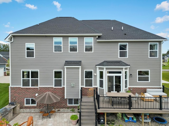 back of house with brick siding, roof with shingles, a patio area, and a wooden deck