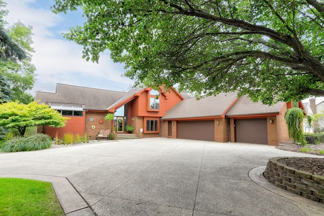 view of front of home featuring a garage, concrete driveway, brick siding, and a shingled roof