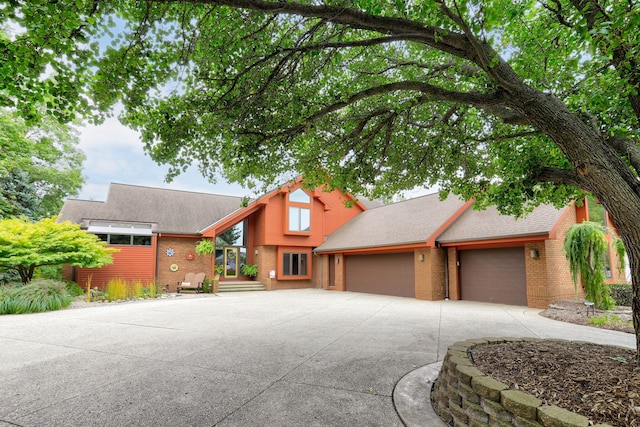 view of front of property featuring a garage, concrete driveway, brick siding, and a shingled roof