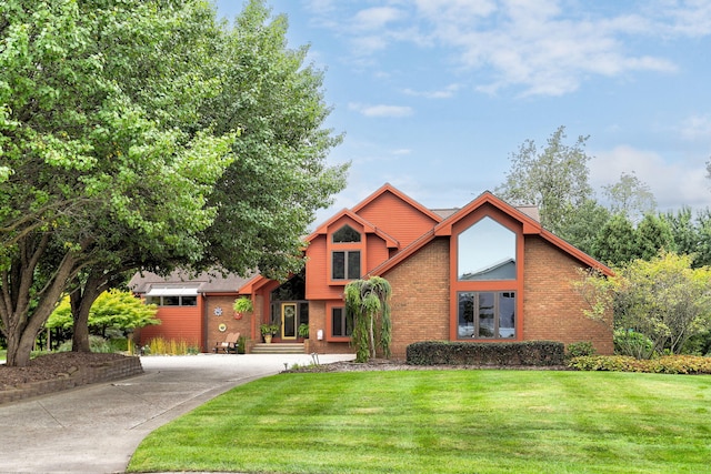 view of front of property featuring concrete driveway, brick siding, and a front lawn