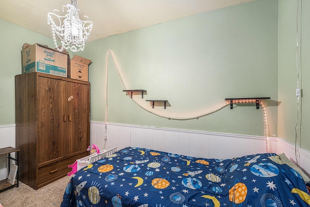 carpeted bedroom with a chandelier and wainscoting