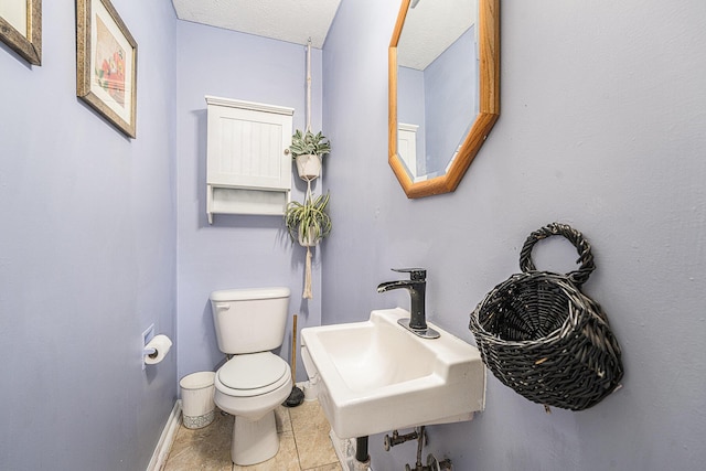 bathroom with toilet, baseboards, a sink, and tile patterned floors