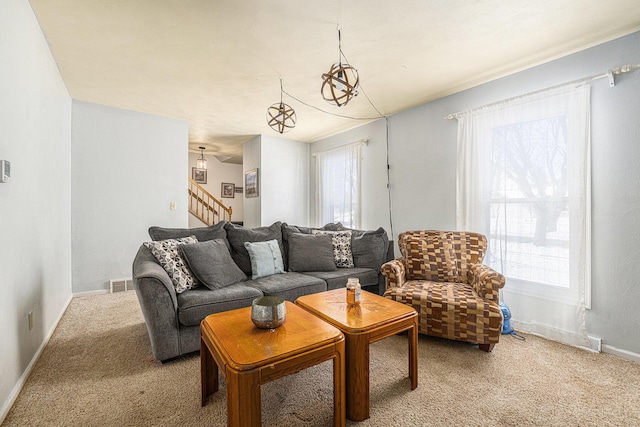 living room featuring carpet floors, stairway, visible vents, and baseboards