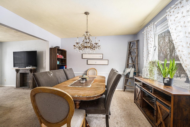 dining room with baseboards, a notable chandelier, and light colored carpet