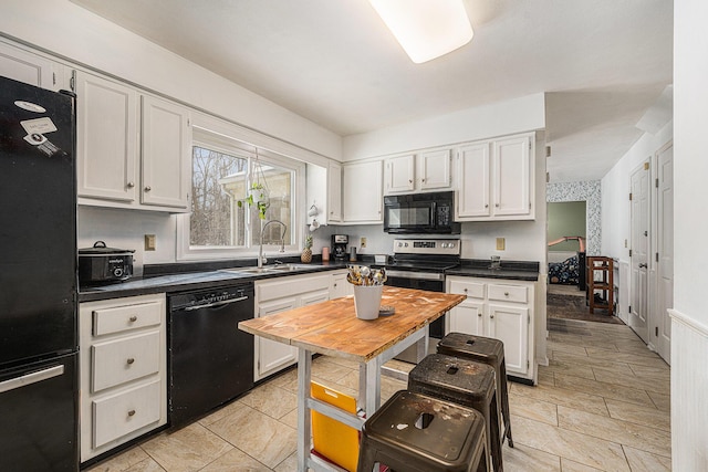 kitchen featuring dark countertops, black appliances, white cabinetry, and a sink