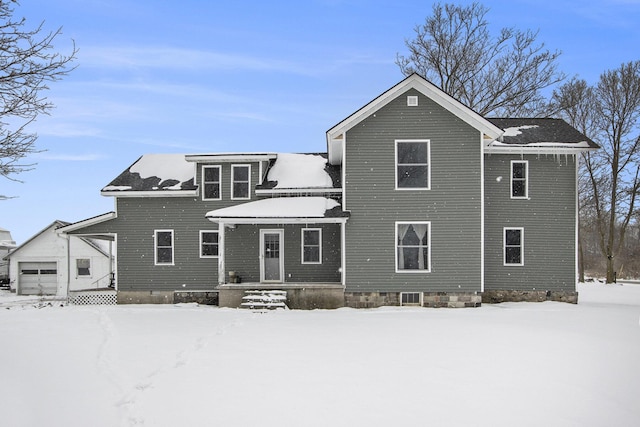 snow covered back of property with an attached garage