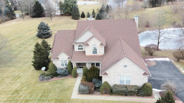 view of front facade with a front yard, stone siding, and a chimney