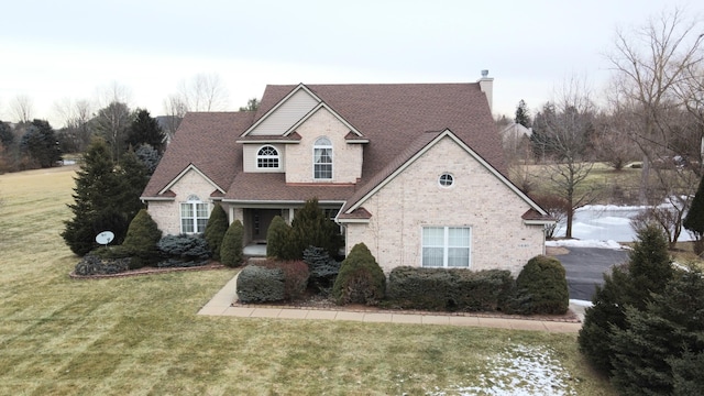 view of front facade with a chimney, a front lawn, and brick siding