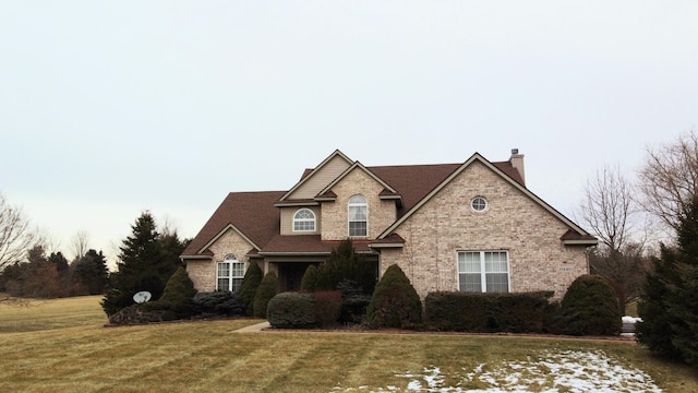 traditional-style house featuring a chimney, a front lawn, and brick siding